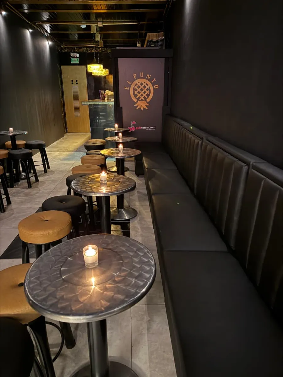 Interior de El Punto bar swinger en Bogotá: mesas con velas y zona lounge en penumbra