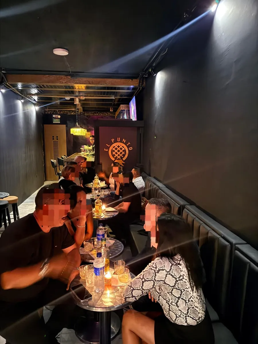 Noche real en El Punto SW: parejas conversando en las mesas del bar swinger de Chapinero, Bogotá