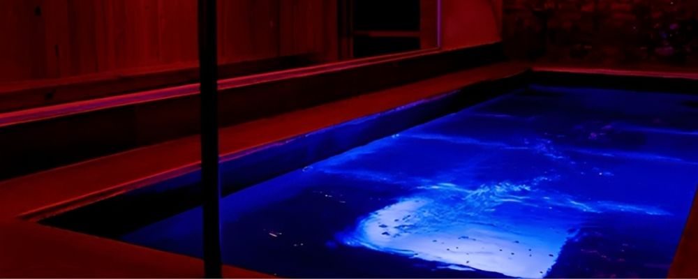 Zonas húmedas de Imperio SW en Bogotá: piscina iluminada en azul junto a un deck de madera bajo luz roja