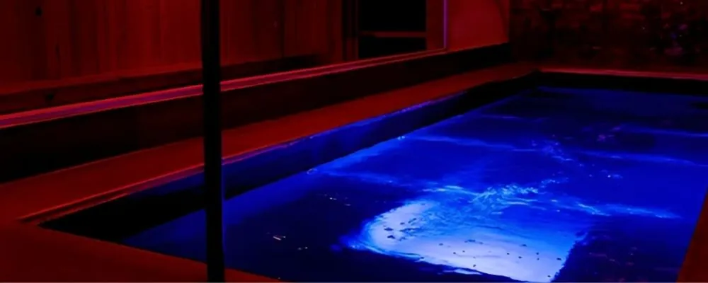 Zonas húmedas de Imperio SW en Bogotá: piscina iluminada en azul junto a un deck de madera bajo luz roja