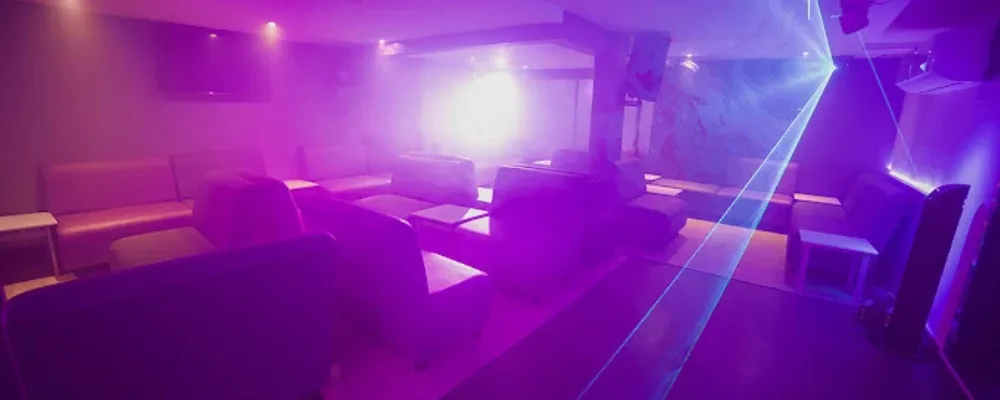 Zona lounge y discoteca de Insolitam Spa en Bogotá, con sofás, luz violeta y láser sobre la pista