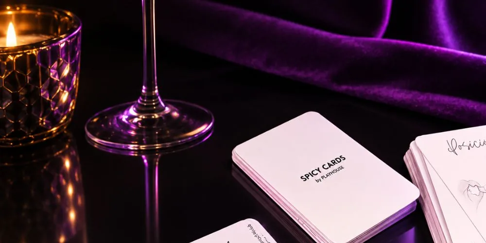 La baraja de Spicy Cards sobre una mesa oscura, junto a una vela y una copa, con terciopelo morado al fondo