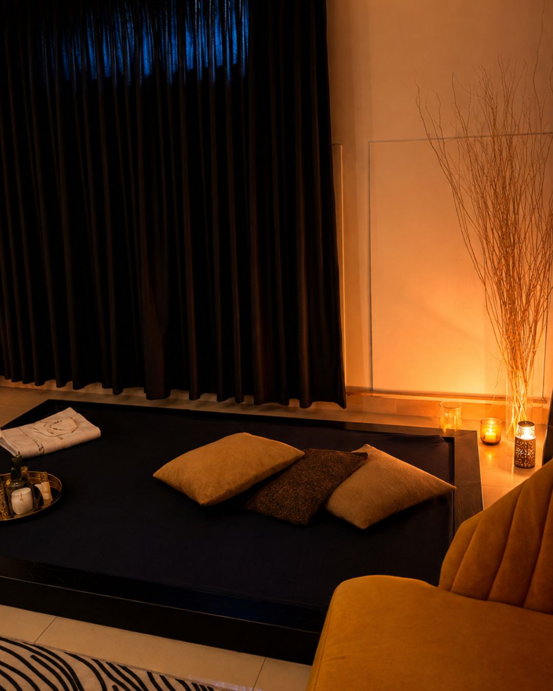 Sala de pareja de Zoe Thai Spa: colchón bajo con cojines, velas y cortinaje oscuro
